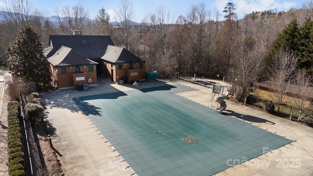 pool with a forest view, a patio, and fence