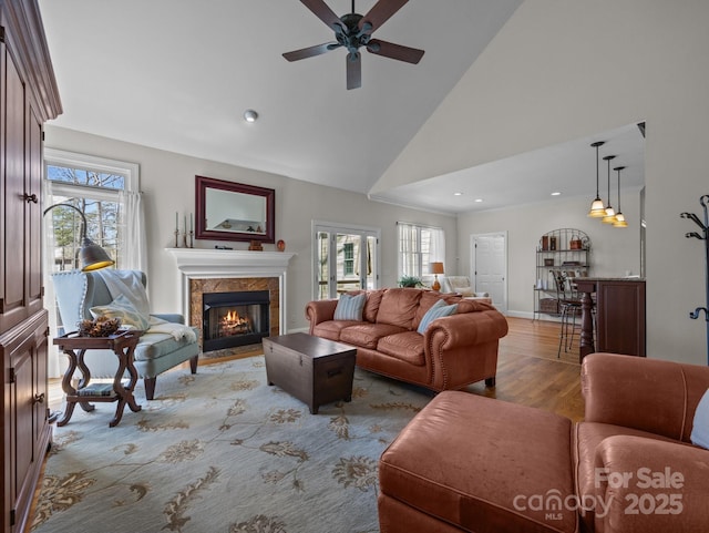 living area featuring light wood-type flooring, plenty of natural light, high vaulted ceiling, and a tile fireplace