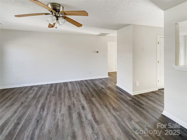 empty room featuring dark wood-style floors, visible vents, a ceiling fan, a textured ceiling, and baseboards