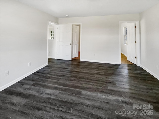 empty room with dark wood finished floors and baseboards