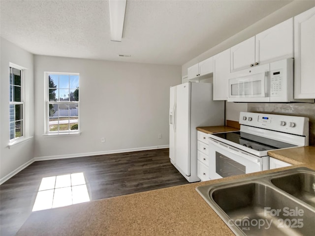 kitchen featuring dark wood-type flooring, white cabinets, a sink, a textured ceiling, and white appliances