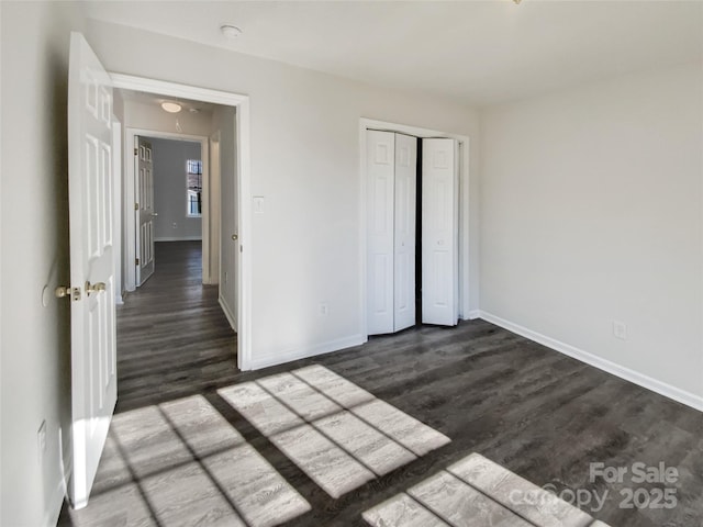 unfurnished bedroom featuring dark wood-style floors, a closet, and baseboards