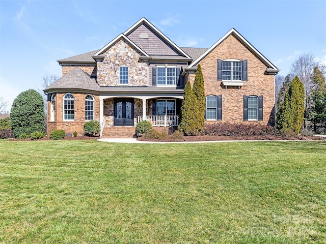 view of front of home featuring brick siding, stone siding, covered porch, and a front lawn