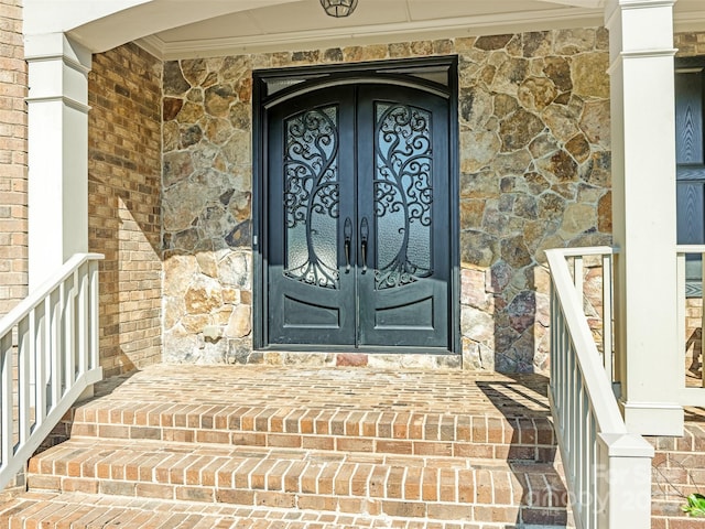 entrance to property featuring french doors, stone siding, and brick siding