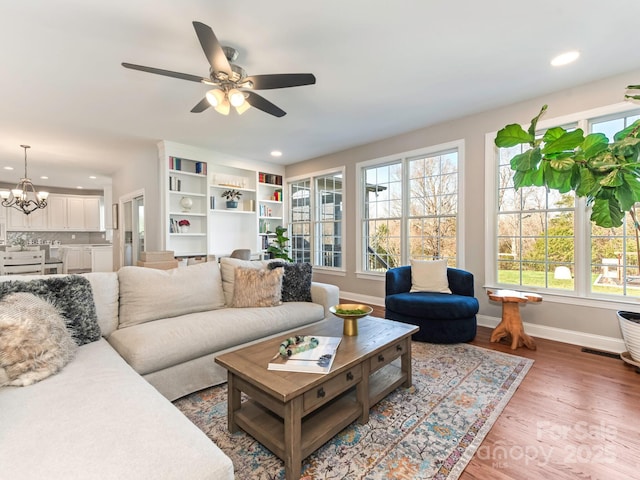 living area featuring visible vents, ceiling fan with notable chandelier, wood finished floors, recessed lighting, and baseboards