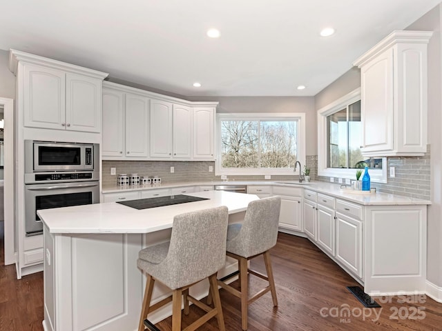 kitchen with a sink, appliances with stainless steel finishes, dark wood-style floors, and white cabinetry