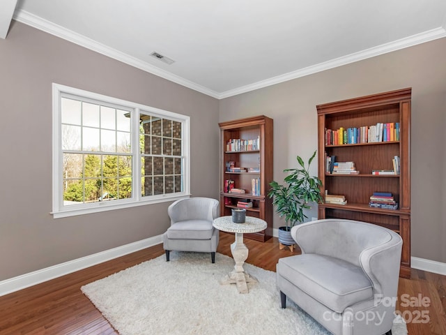 sitting room with crown molding, wood finished floors, visible vents, and baseboards