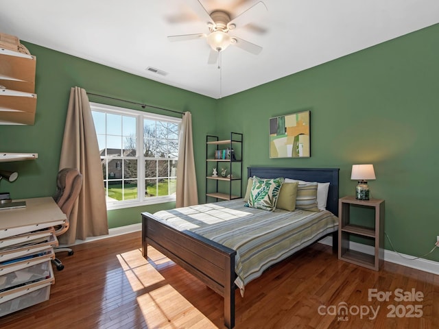 bedroom featuring visible vents, ceiling fan, baseboards, and wood finished floors