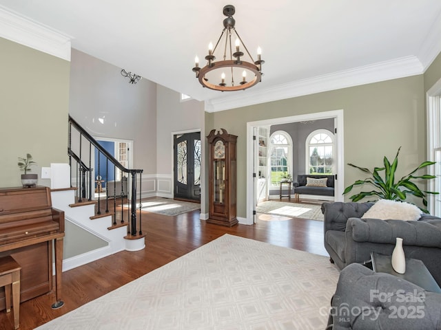 foyer featuring an inviting chandelier, stairway, wood finished floors, and crown molding