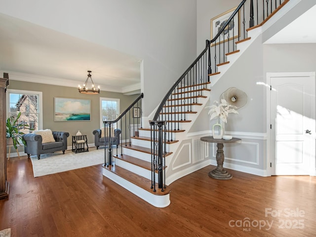 staircase featuring wood finished floors, a wealth of natural light, and ornamental molding