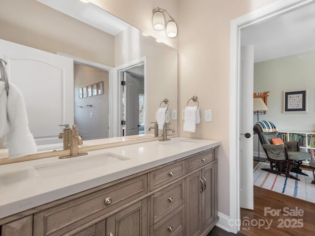 bathroom featuring double vanity, wood finished floors, baseboards, and a sink