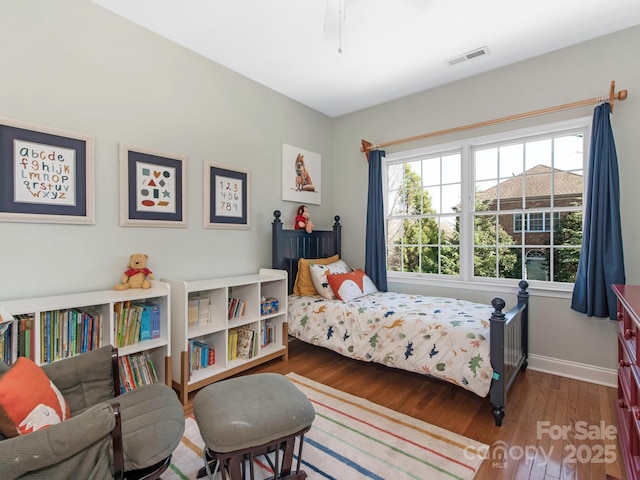 bedroom with visible vents, baseboards, and wood finished floors