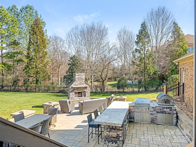 view of patio / terrace featuring fence, area for grilling, exterior kitchen, and an outdoor living space with a fireplace