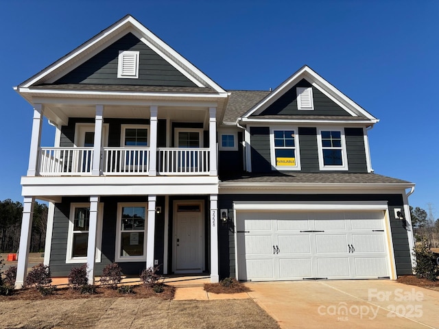 view of front of property featuring concrete driveway, a balcony, a garage, and a shingled roof