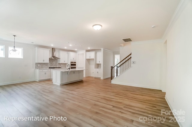 unfurnished living room with light wood finished floors, visible vents, baseboards, stairs, and recessed lighting