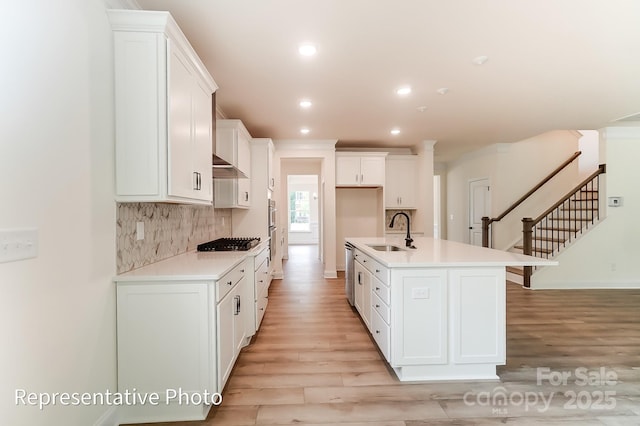 kitchen with black gas stovetop, a sink, tasteful backsplash, stainless steel dishwasher, and exhaust hood