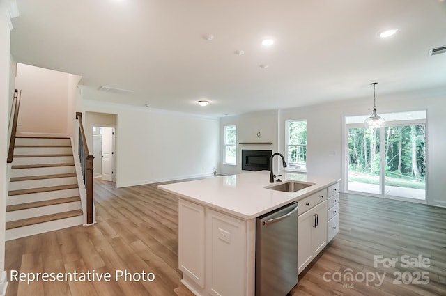 kitchen with a sink, light wood-style floors, dishwasher, and white cabinets