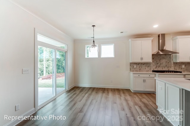 kitchen with backsplash, black stovetop, light countertops, white cabinets, and wall chimney exhaust hood