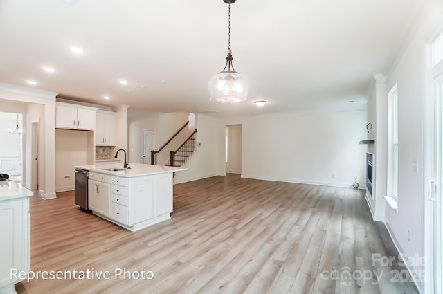 kitchen featuring open floor plan, dishwasher, light countertops, and a sink