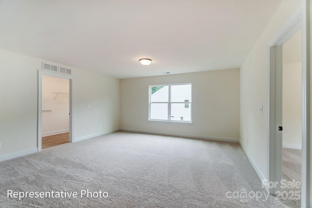 carpeted spare room featuring visible vents and baseboards