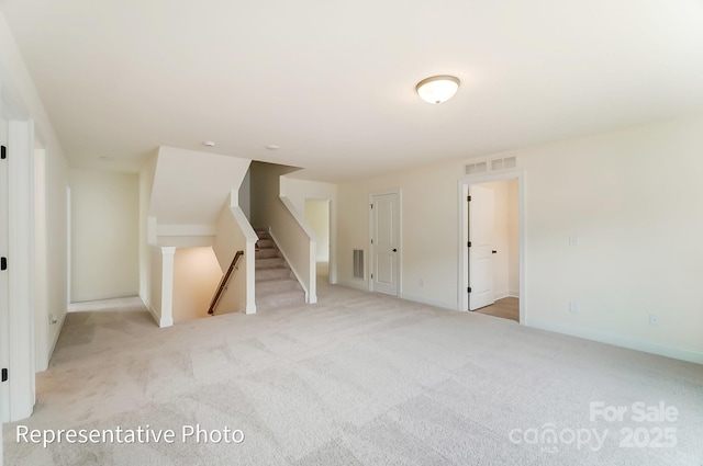 spare room featuring stairway, light colored carpet, and visible vents