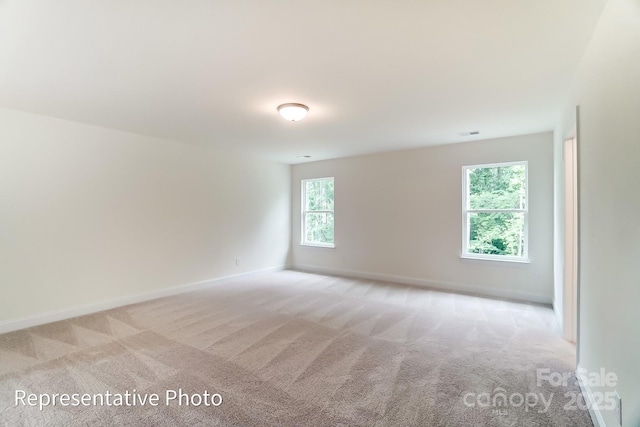 spare room with light carpet, visible vents, and baseboards