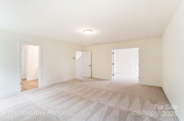 spare room with light colored carpet and baseboards