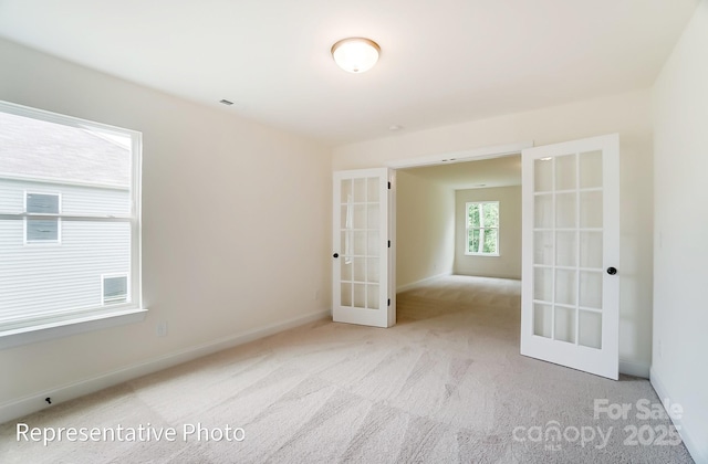 carpeted spare room with french doors and baseboards