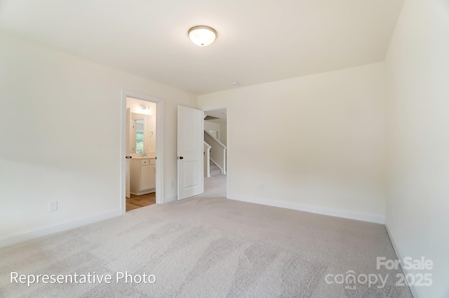 unfurnished room with baseboards and light colored carpet