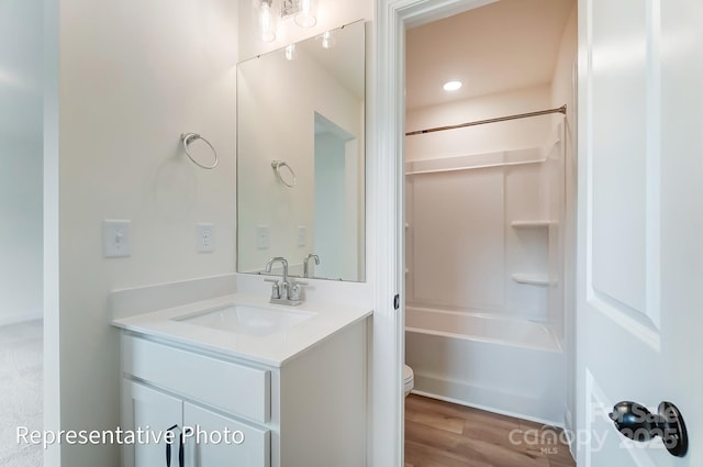 full bath with shower / tub combination, wood finished floors, vanity, and toilet