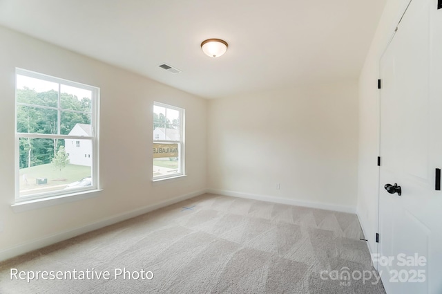 empty room with visible vents, baseboards, and light colored carpet