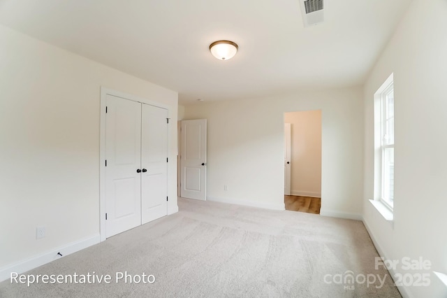 unfurnished bedroom featuring a closet, visible vents, baseboards, and carpet floors