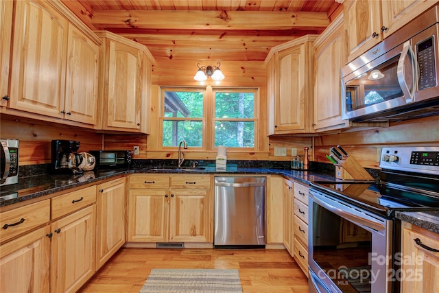 kitchen featuring beamed ceiling, light brown cabinets, a sink, light wood-style floors, and appliances with stainless steel finishes