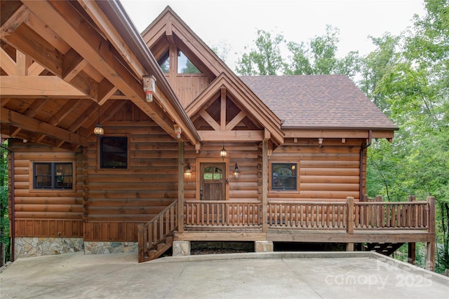 view of front of home featuring log exterior and roof with shingles