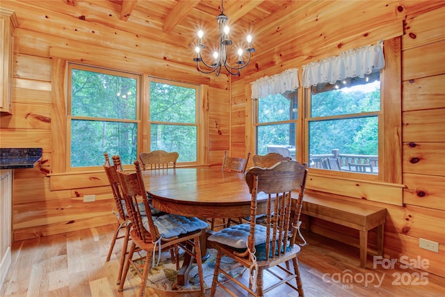 dining space featuring beamed ceiling, a notable chandelier, wood ceiling, and light wood-style floors