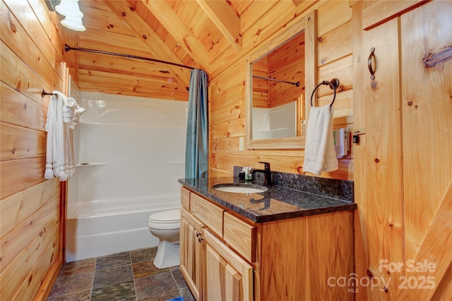 bathroom with vanity, stone finish floor, wood walls, toilet, and shower / tub combo with curtain