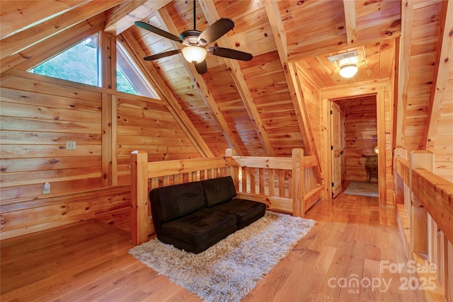 living area with an upstairs landing, wood walls, wooden ceiling, and light wood-style floors