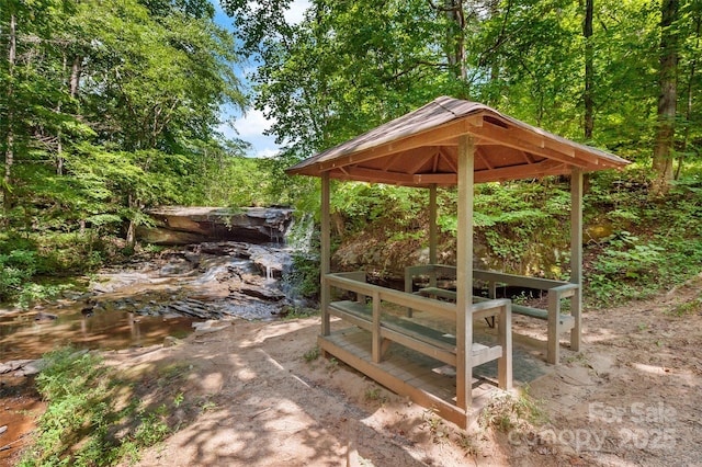 view of patio / terrace featuring a gazebo and a view of trees