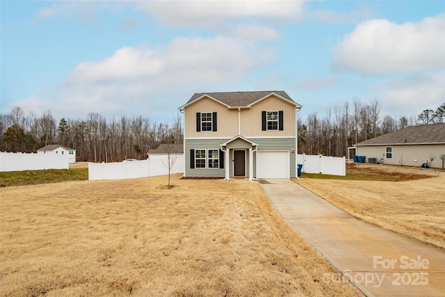 traditional home with driveway, an attached garage, fence, and a front lawn