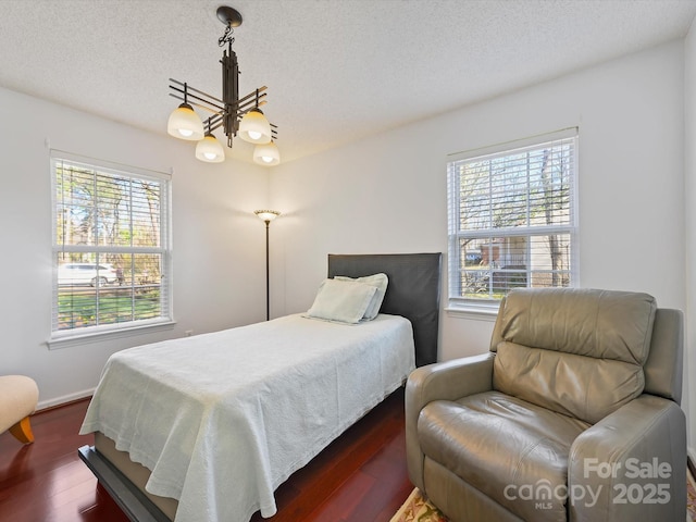 bedroom with dark wood finished floors, a notable chandelier, a textured ceiling, and baseboards