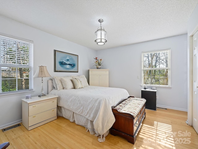 bedroom with visible vents, a textured ceiling, and light wood-type flooring