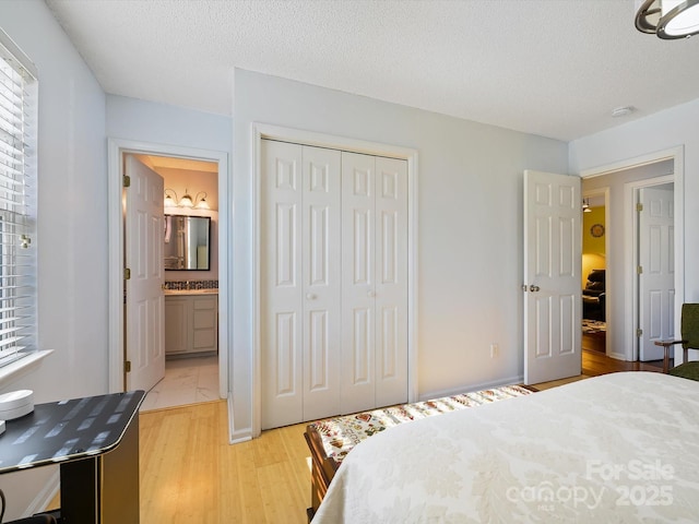 bedroom with a closet, light wood finished floors, a textured ceiling, and ensuite bathroom