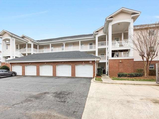 view of front of home with a shingled roof, aphalt driveway, and brick siding