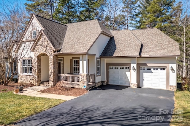 view of front of home featuring a shingled roof, aphalt driveway, a porch, stone siding, and an attached garage