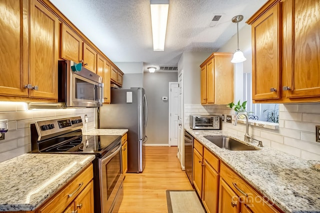 kitchen with visible vents, brown cabinets, stainless steel appliances, and a sink