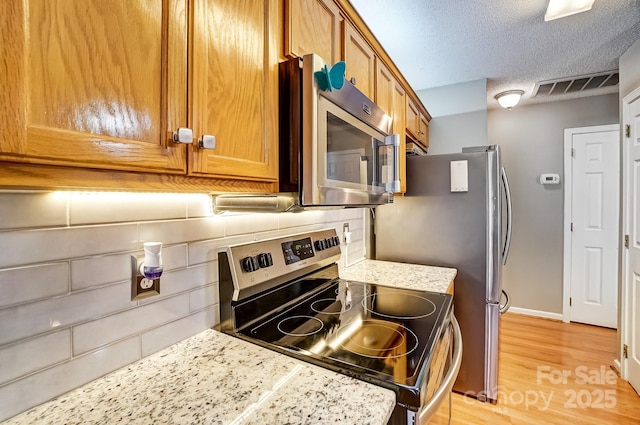 kitchen with visible vents, brown cabinets, a textured ceiling, and stainless steel appliances