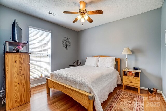 bedroom featuring visible vents, baseboards, and wood finished floors