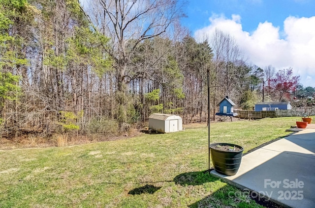 view of yard featuring a storage unit, an outdoor structure, and fence