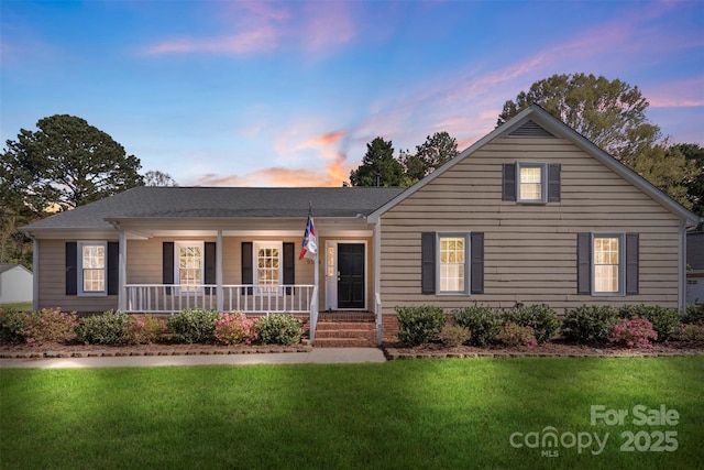 single story home featuring a porch, a shingled roof, and a yard