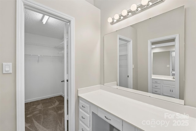 full bathroom with vanity, a spacious closet, and a textured ceiling